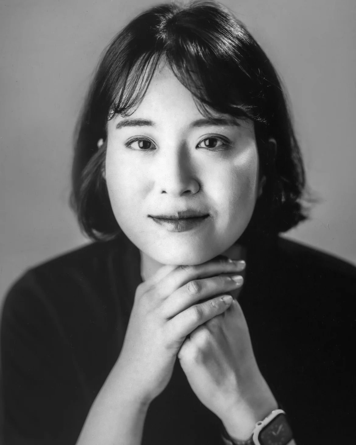 두 손을 턱 아래 모으고 정면을 바라보는 김진의 흑백 초상